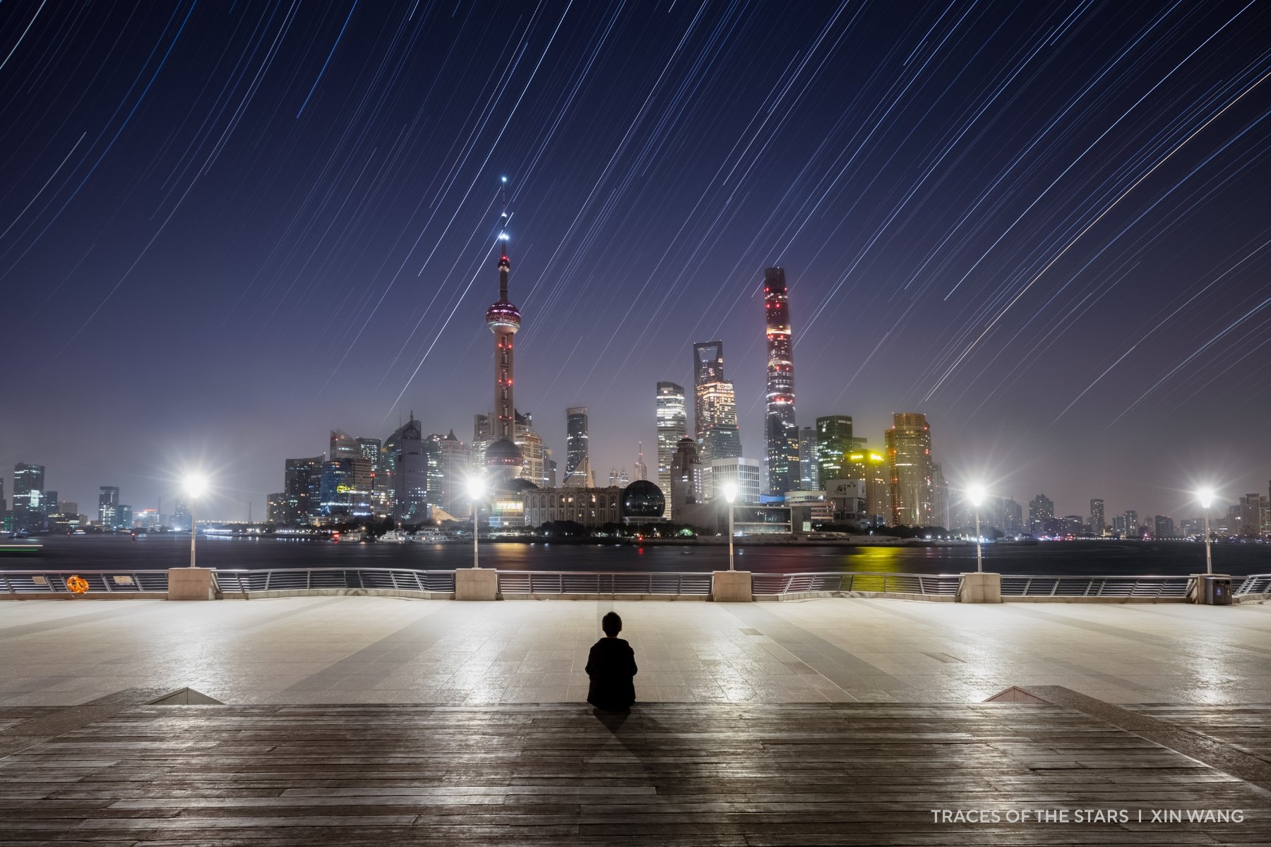A cityscape with a few star trails above.