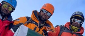 Climbers on a snowy place, apparently a summit, with the sky above them.