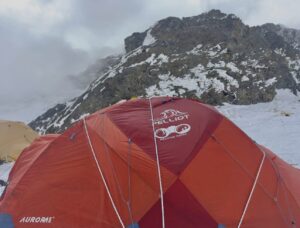 A red tent on mixed terrain on K2 in a cloudy day.