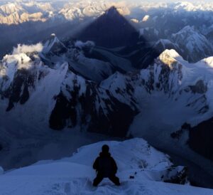 A climber goes down a snow slope on K2 under the shadow of the mountain's summit.