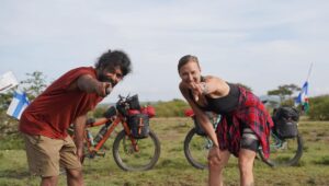 man and woman point at camera beside bikes