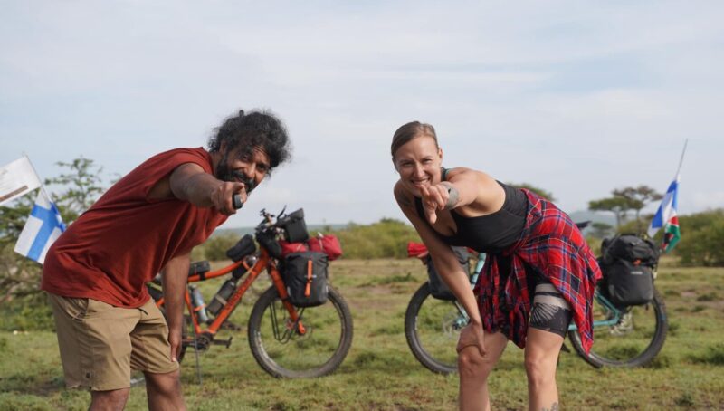 man and woman point at camera beside bikes
