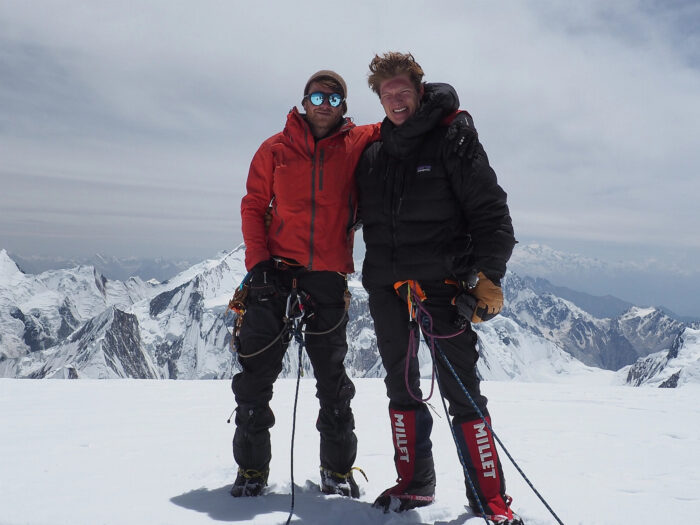 Two climbers stand on the summit of Spantik