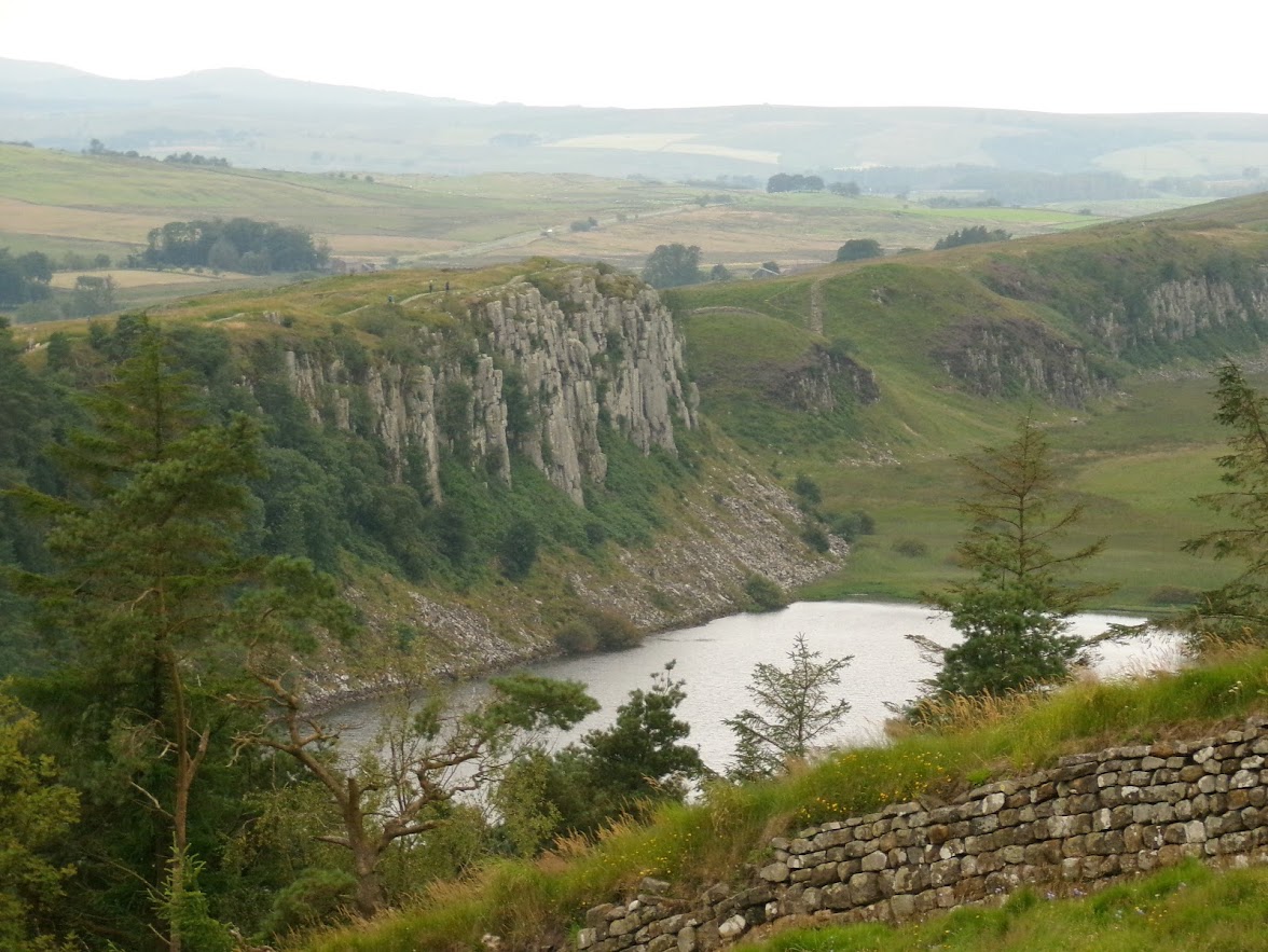 A cliff overlooking a lake with a wall in the foreground.