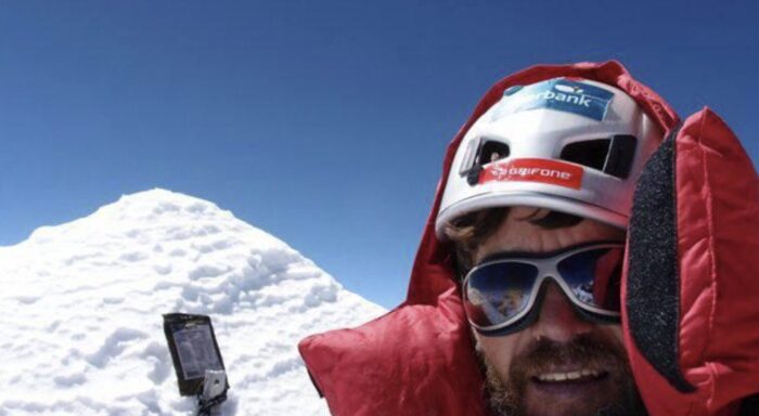 Close shot of a climber on a spiky summit and a electronic device on the snow. 