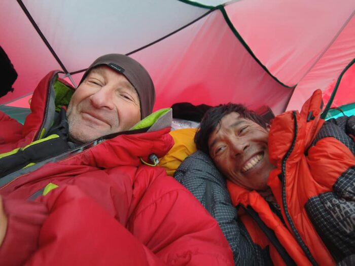 Climbers in a tent with dawn jackets. 