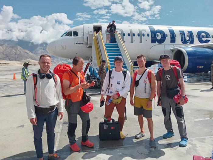 A climbing team stands in front of an airplane.