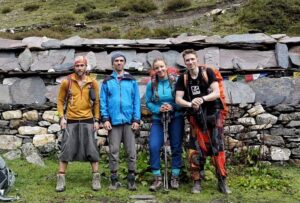 Russian team members pose standing in front of a stone wall in Nepal.