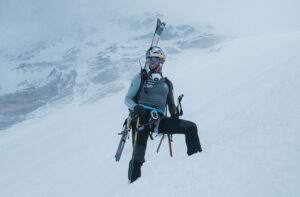 Bargiel on Everest, feet sunk in fresh snow and skis on his back, in a foggy day