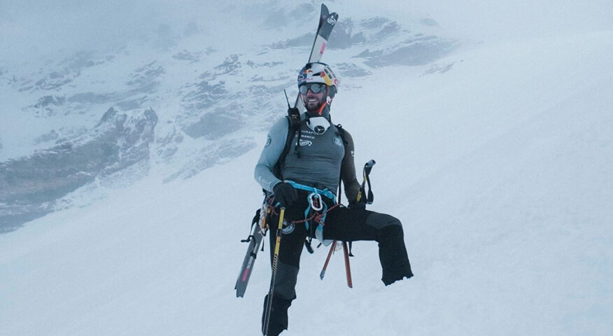 Bargiel on Everest, feet sunk in fresh snow and skis on his back, in a foggy day