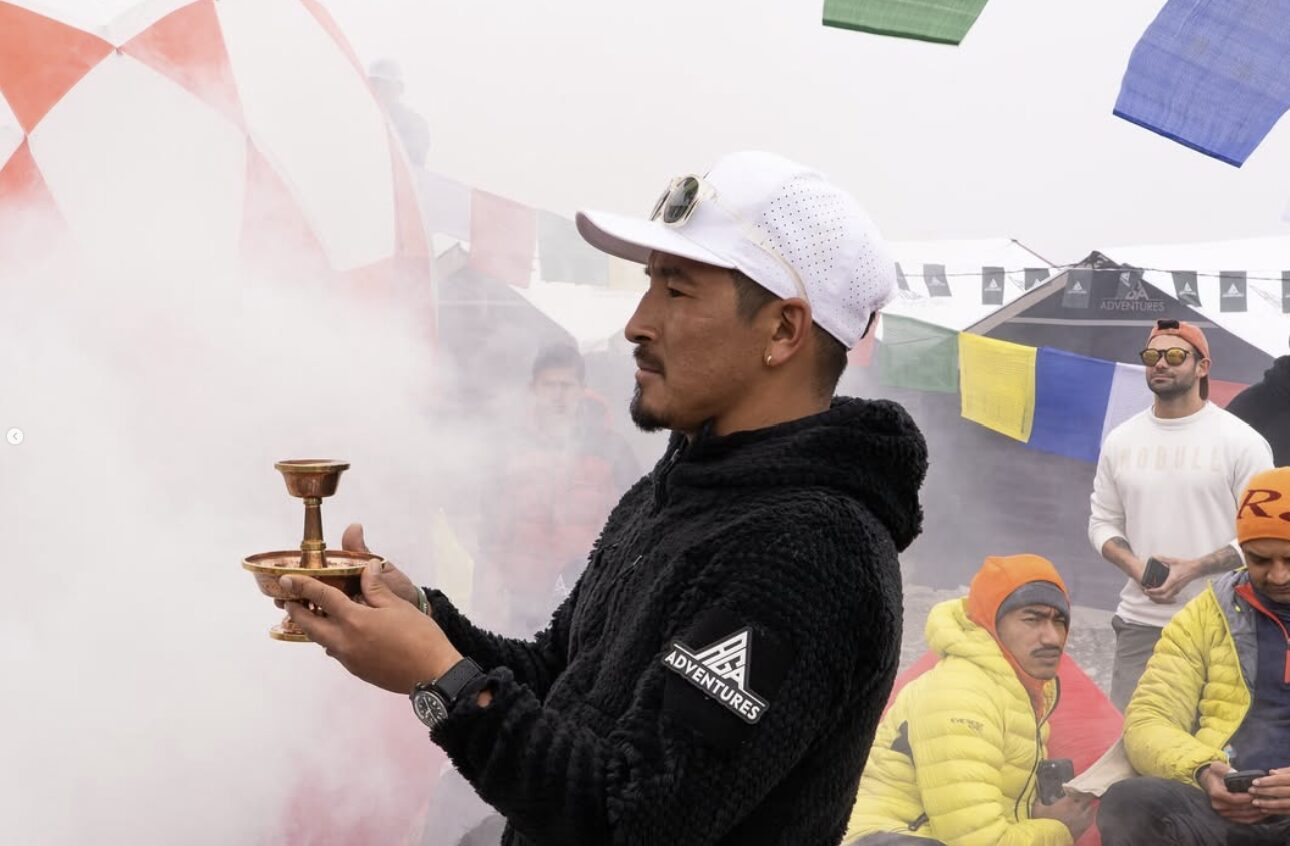 Gelje Sherpa holds a golden offering object at a base camp wrapped in the smoke of juniper bonfires.