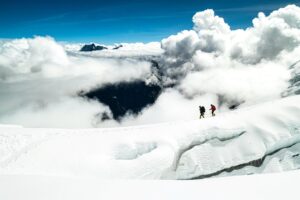 Two climbers on the summit ridge of Manaslu, clouds behind.