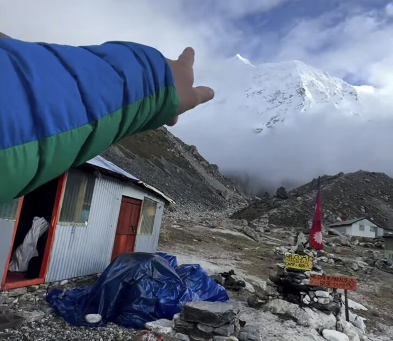 climber's arm points toward snowy Makalu summit