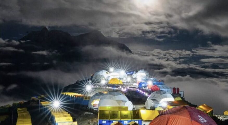 Tents with lights in the moonlight.