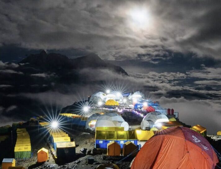 Tents with lights in the moonlight.