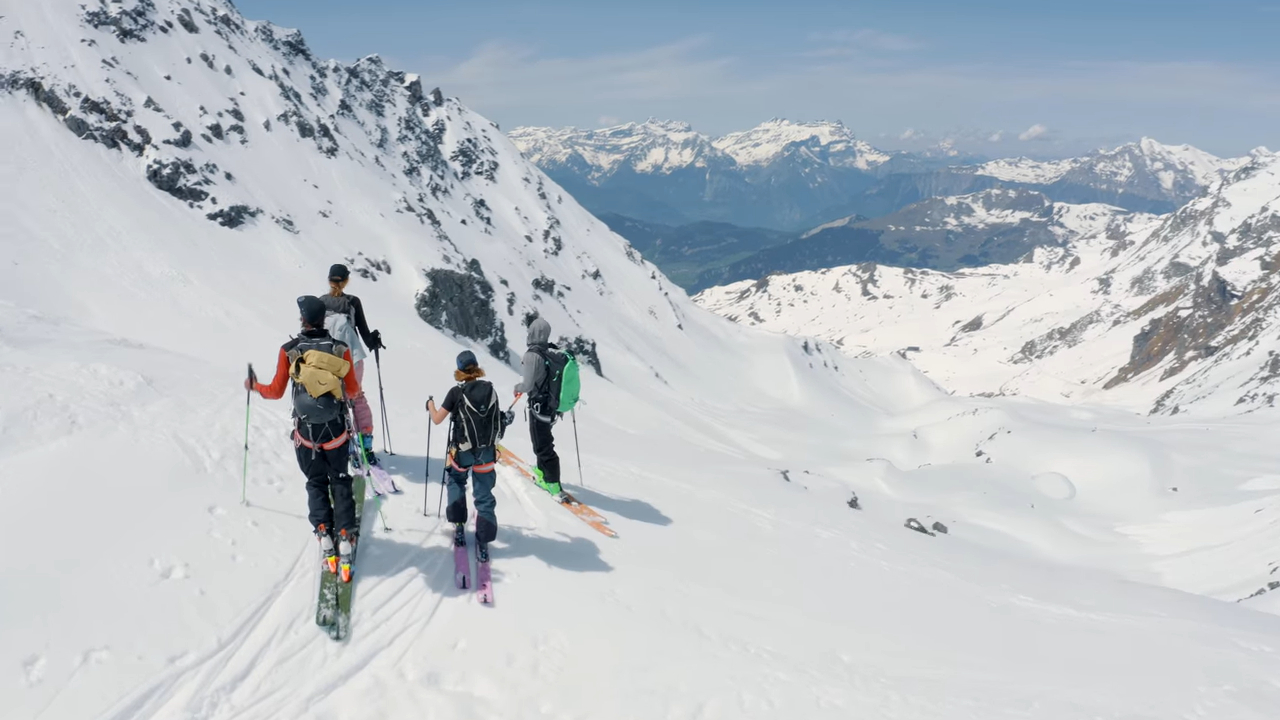 Four people with skis on a mountainside
