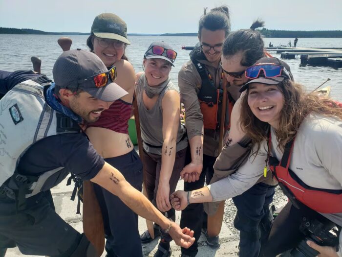 The six paddlers showing off matching tattoos.
