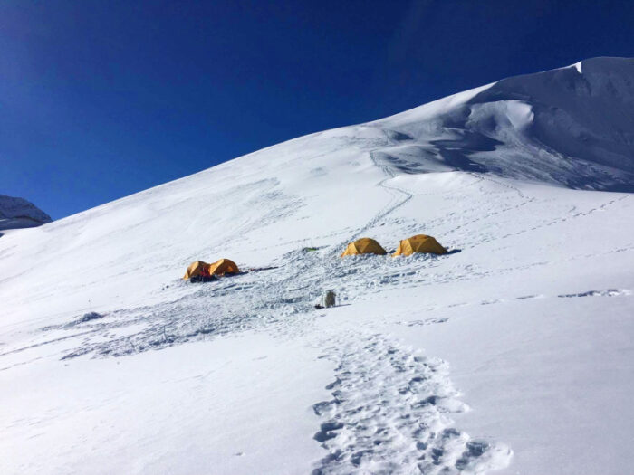 four tents on a wide snow slope. 