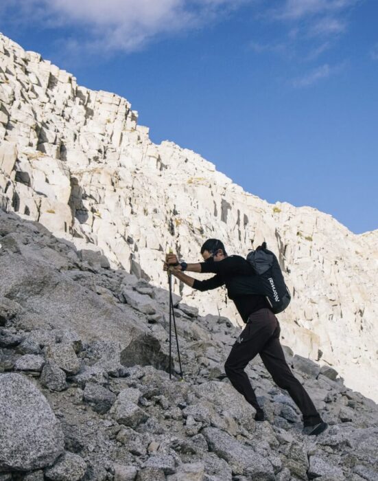 Jornet progress up a granite rock slope with hiking poles. 