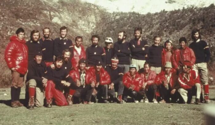 Old photo of an expedition team in 1970's clothes posing on a green field. 