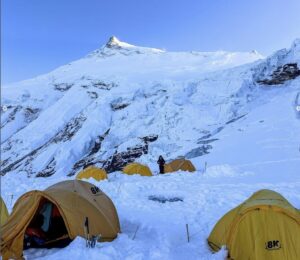 Some tents on the snow with Manaslu's summit in the background.