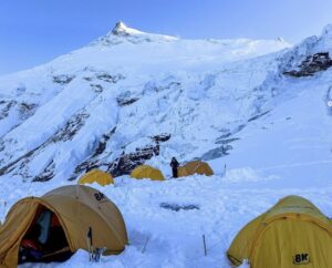 Some tents on the snow with Manaslu's summit in the background.