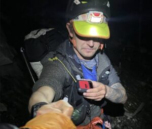 Andrews with a t-shirt and helmet, shakes hands with a member of his team in then night at Everest Base Camp.