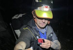 Andrews with a t-shirt and helmet, shakes hands with a member of his team in then night at Everest Base Camp.
