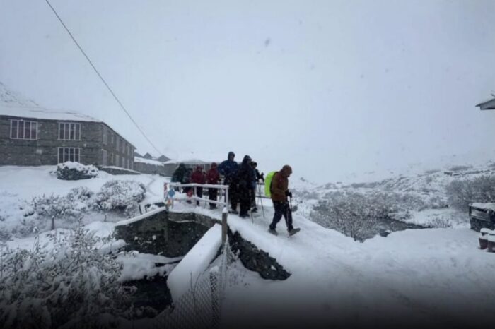 Trekkers in a fogy day on a snow covered stone bridge.