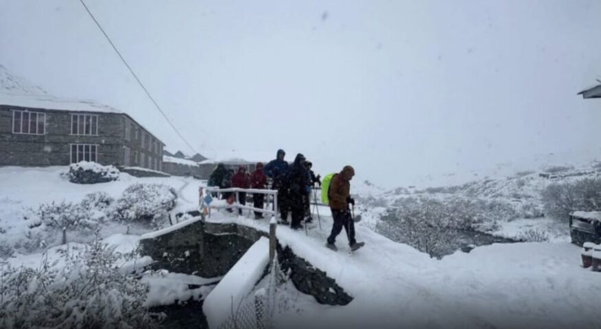 Trekkers in a fogy day on a snow covered stone bridge.