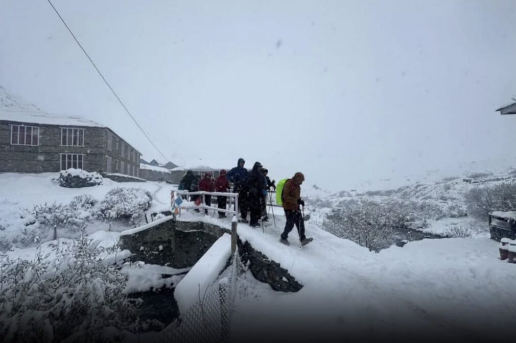 Trekkers in a fogy day on a snow covered stone bridge.
