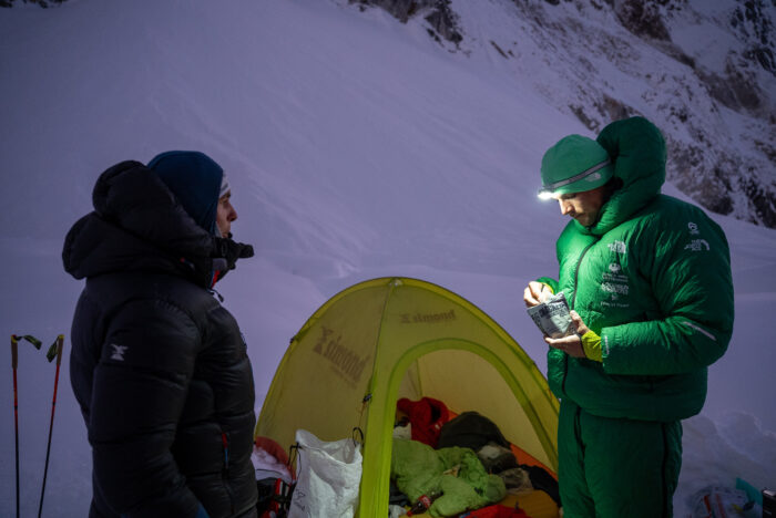 jean and Vedrines standing in front of a small yellow tent in the dimming light of dawn.