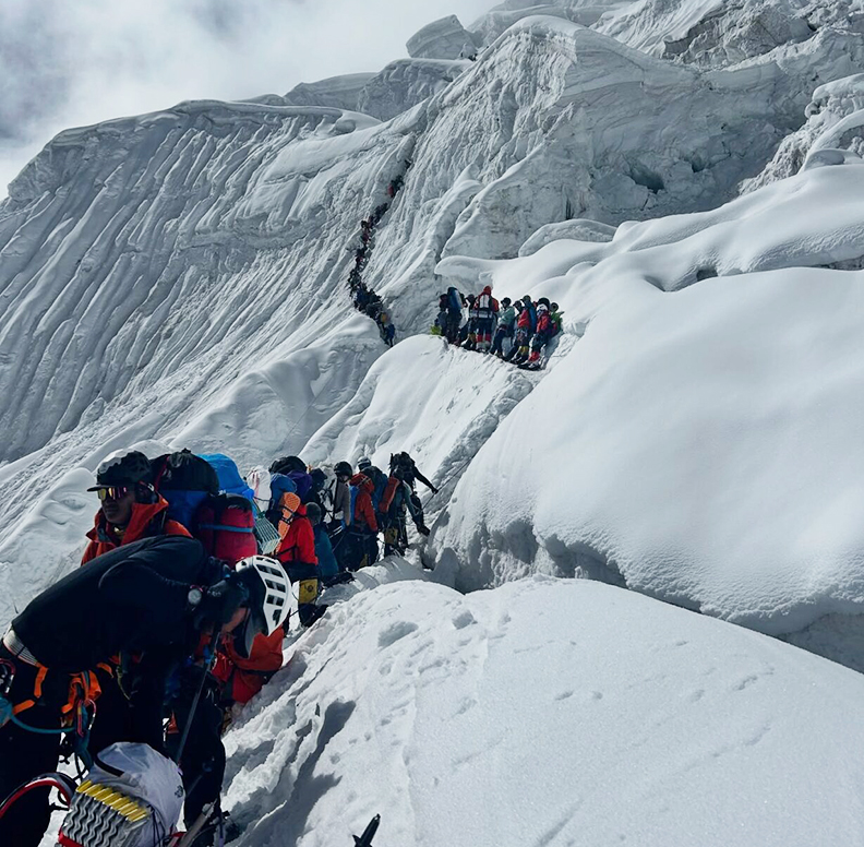long line of climbers going up snowy mountain