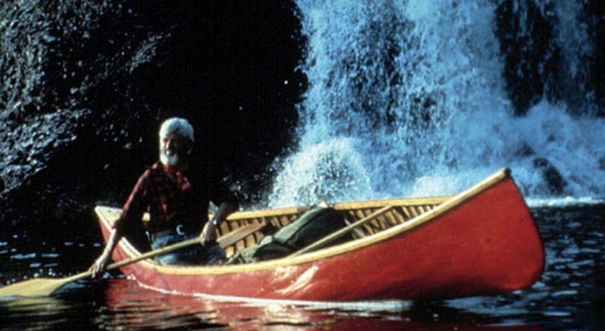man canoeing by waterfall