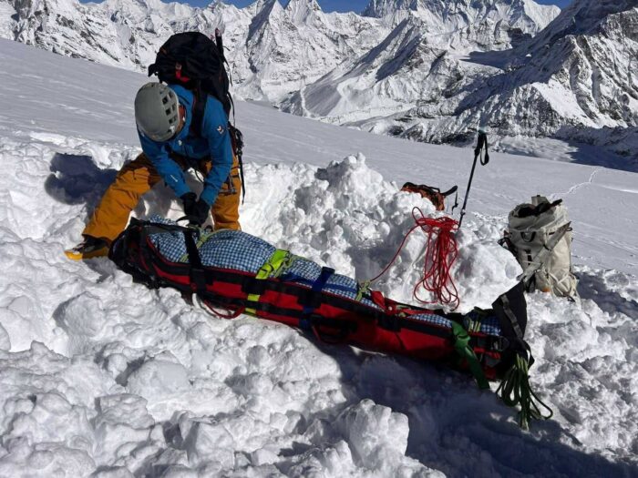 a rescuer secures the body of a climber wrapped in a folder. 