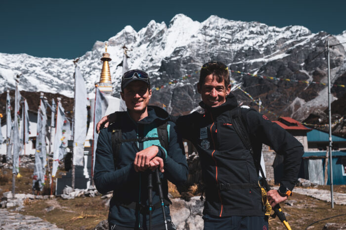 The clibmers posing in front of a chorten and snowy peaks in background.