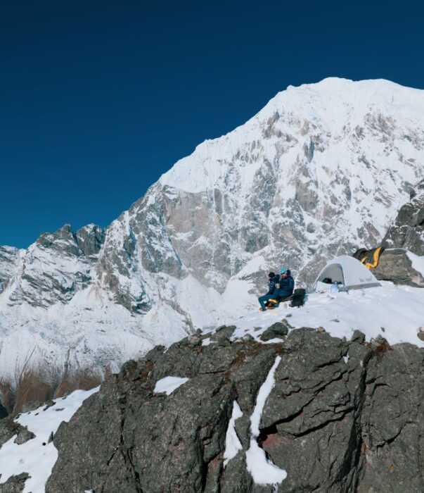 The climbers by a tent on top of a cliff.