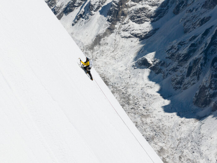 A climber on a snow ramp ending in a void.
