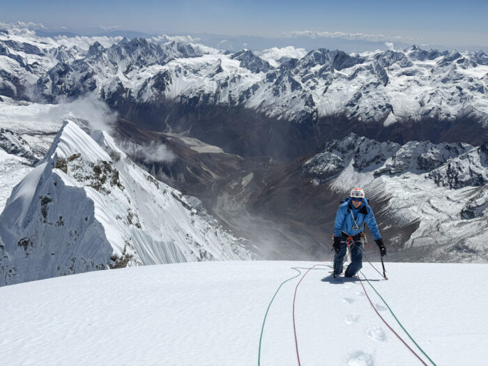 A climber on a mild snow ramp, roped up.