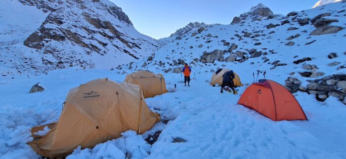 Tents on the snow in a lonely mountain setting.
