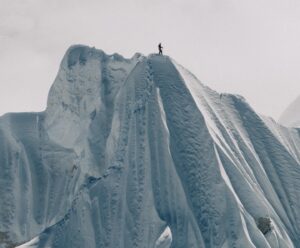 The shillouette of a climber on the top of a huge snow cornice.