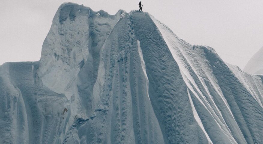 The shillouette of a climber on the top of a huge snow cornice.