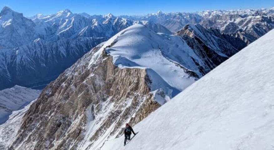 a climber at the end of the rope, traverses below snow ridge.