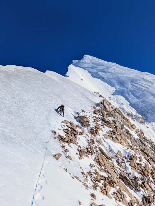 A climbers leading a pitch on a snow/ice ridge. 