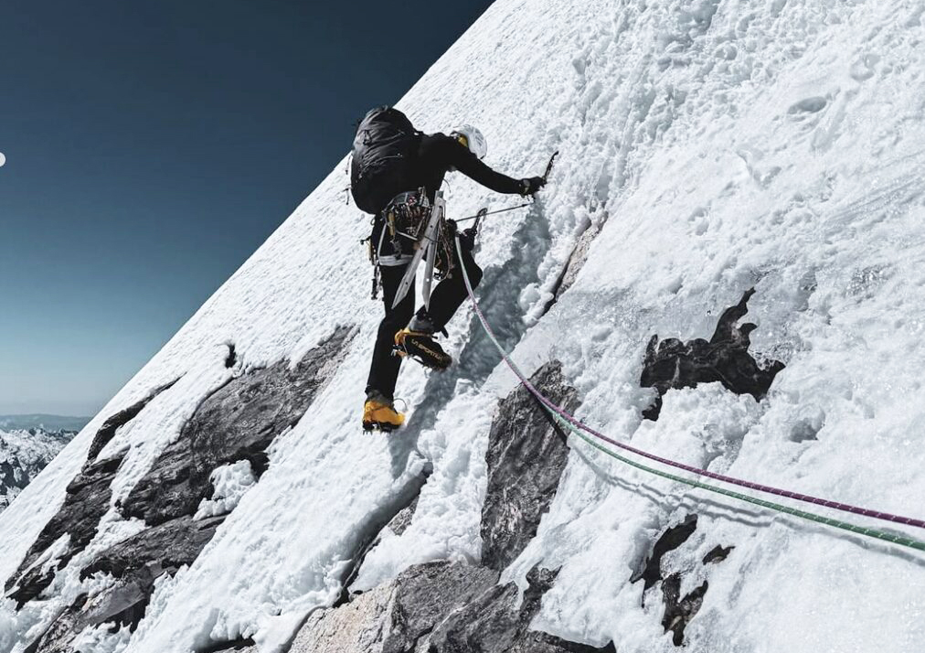 roped climber proceeding up steep snowy slope
