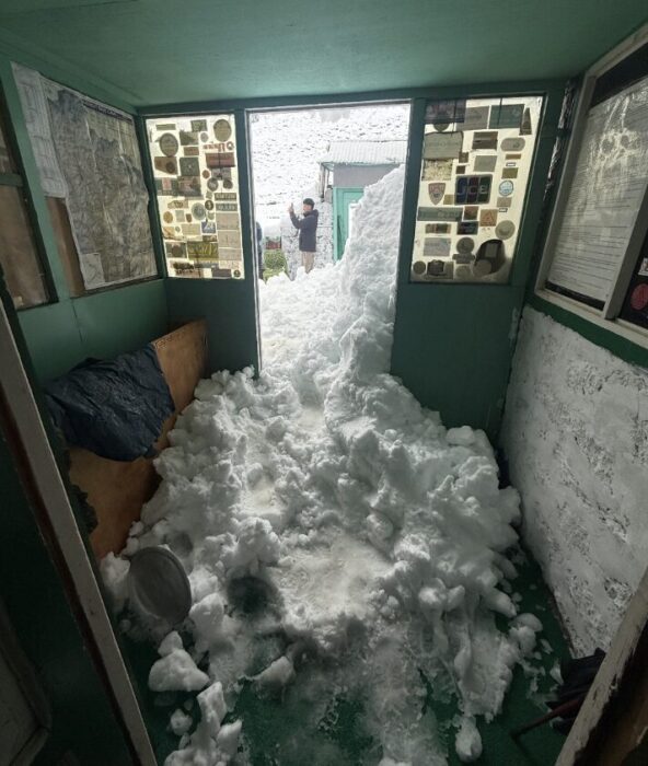 loads of snow entering a lodge after avalanching from the roof. 