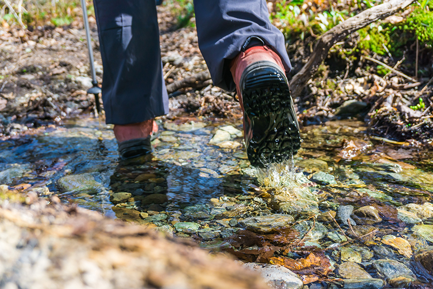 closeup of legs and boots of hiker in stream