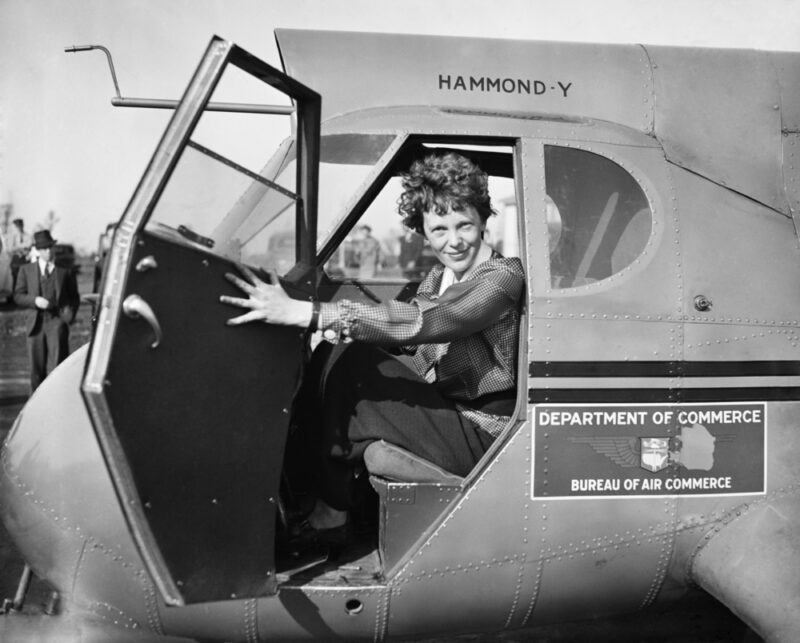 A black and white photo of Amelia Earhart in a Department of Commerce airplane.