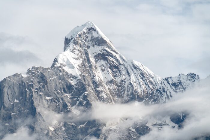 A spiky summit with rags of clouds underneath.