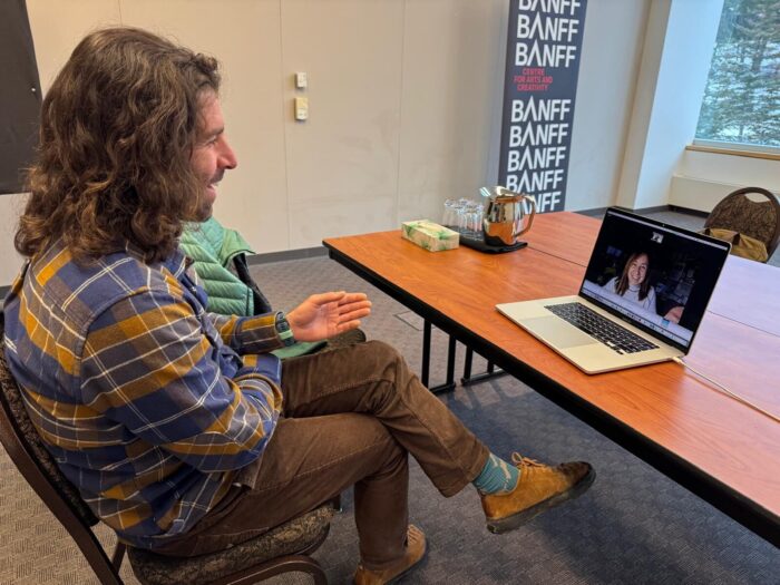 Millerioux sits at an office in front of a computer, with an ExWeb's journalist on the screen.